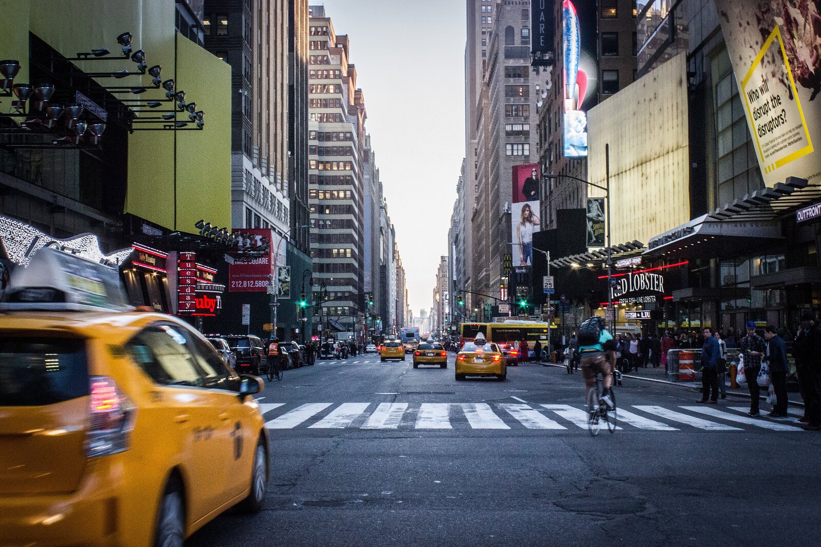 Rušná ulice v New Yorku se žlutými taxíky, chodci a vysokými budovami