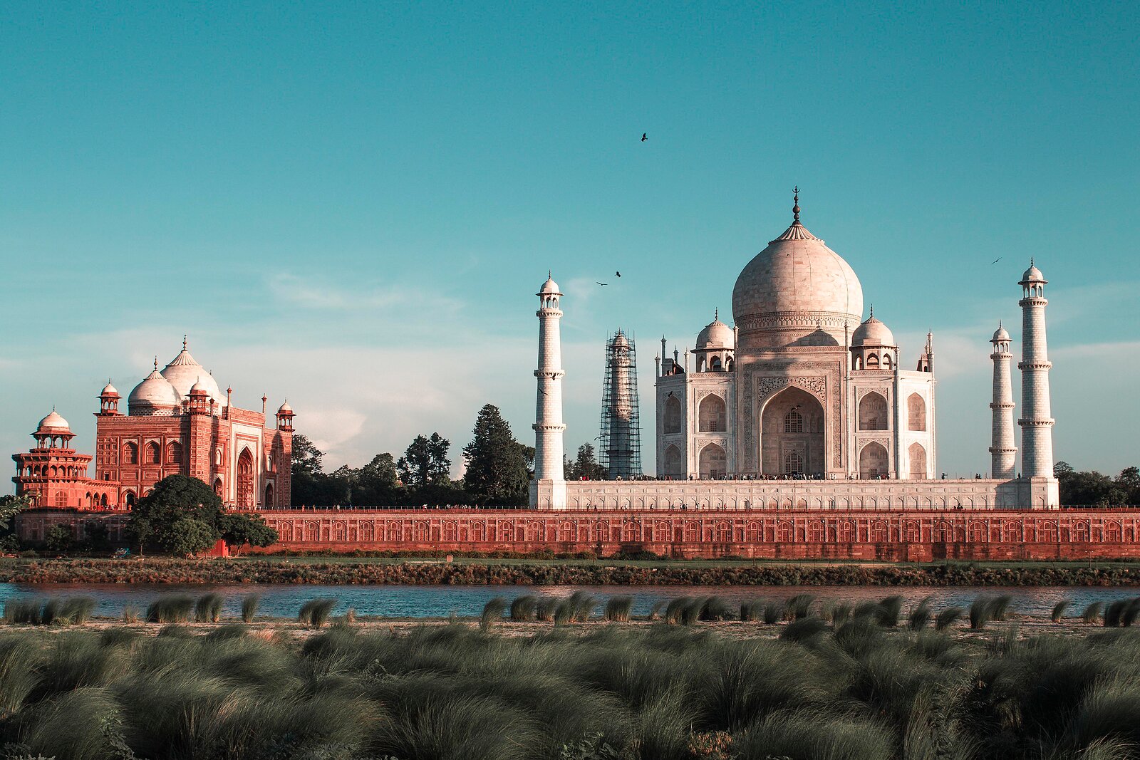 Tádž Mahal s minarety, červenou mešitou a řekou Jamunou v popředí.