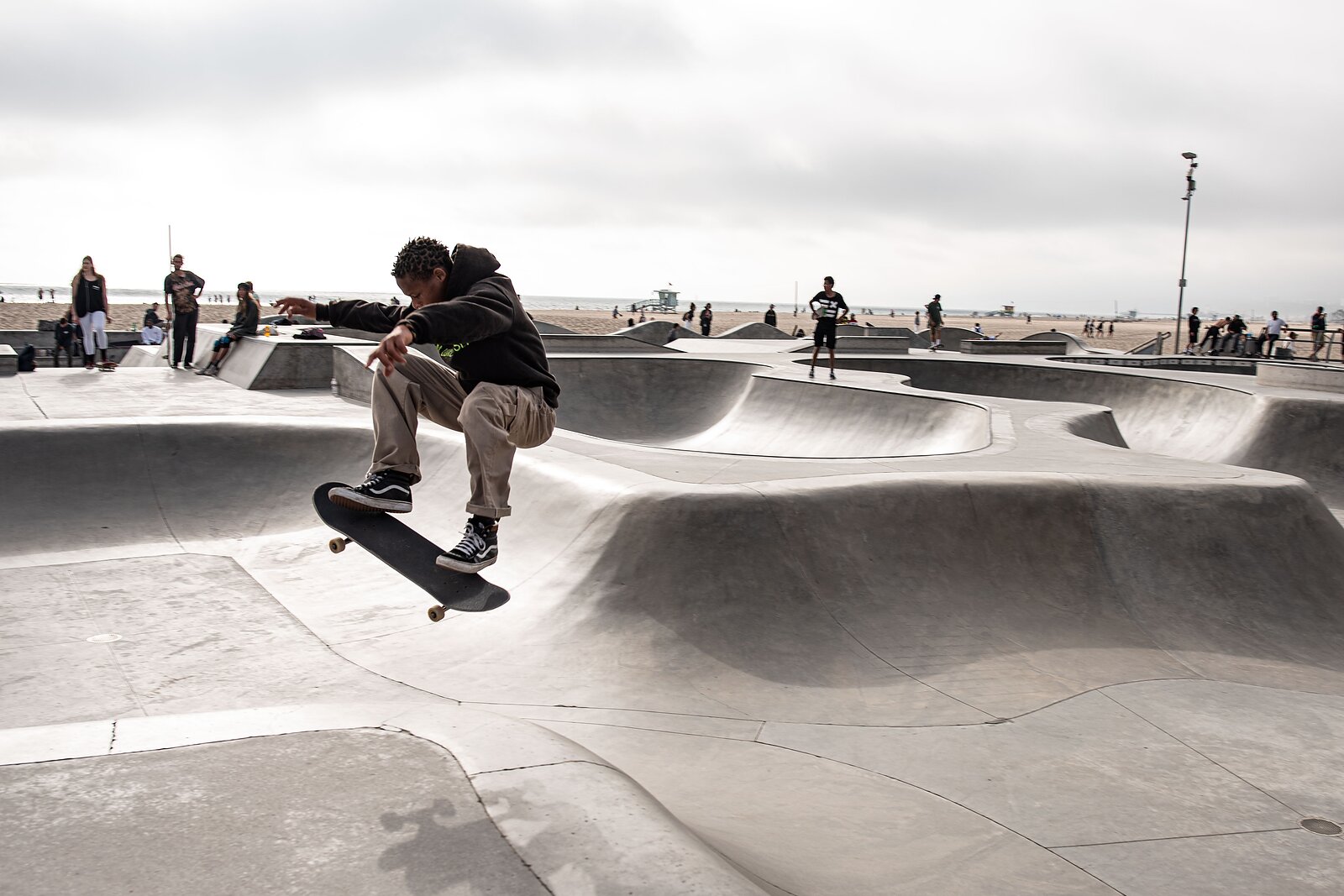 Skateboardista ve vzduchu při triku nad betonovou rampou ve skateparku u moře